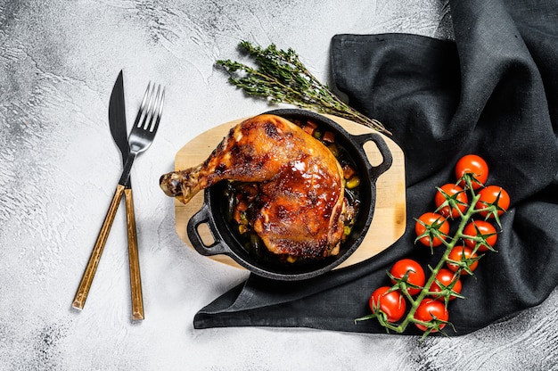 Baked chicken leg with seasonings in a frying pan. Gray background. Top view