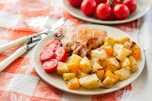 Baked chicken thigh with baked potatoes and pumpkin garnish on a plate