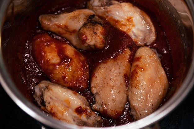 Baked chicken wings covered in barbecue sauce glaze application stage