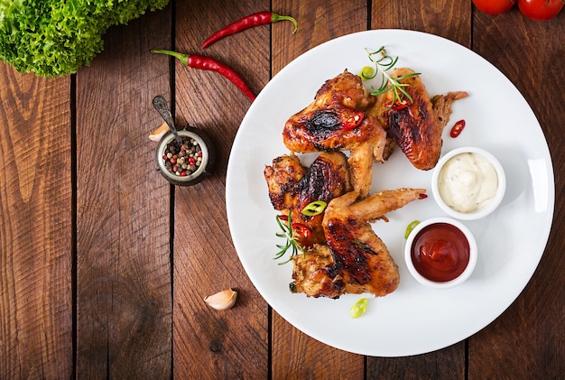 Baked chicken wings in pan on wooden table.