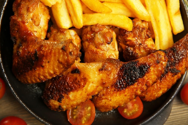 Baked chicken wings with French fries close up