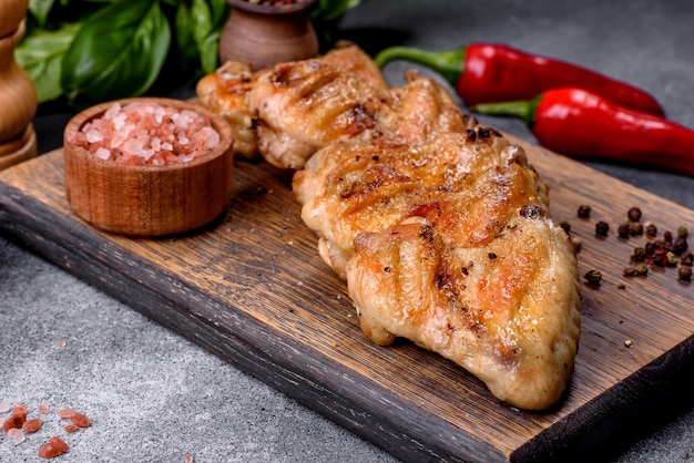 Baked chicken wings with sesame seeds and sauce on a wooden cutting board