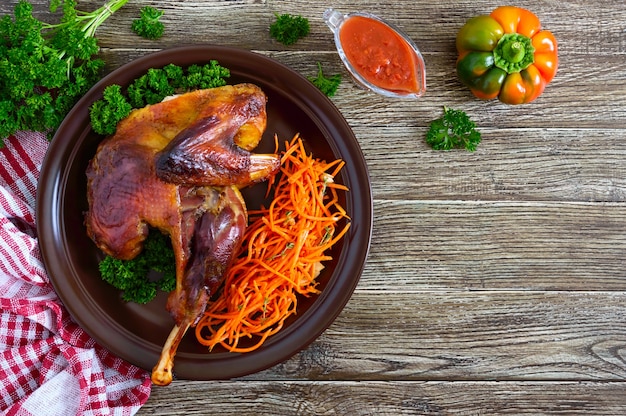 Baked chicken with a golden crispy crust and fresh carrot salad on a ceramic plate. The top view. Flat lay