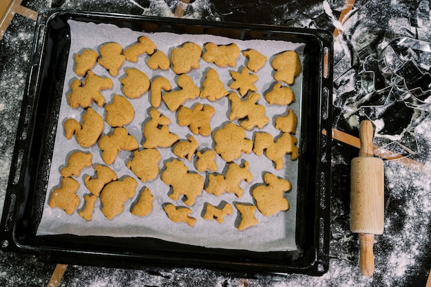 Photo baked christmas cookies lie on baking paper on a tray on a floured table top view