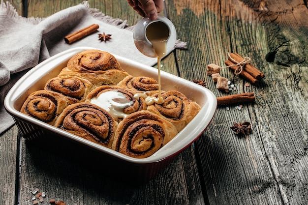 Baked cinnamon buns with with vanilla cream, swedish dessert on a wooden table. Food recipe background. Close up