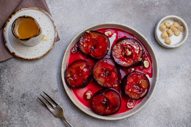 Baked colorful plums with honey, cinnamon and hazelnuts. Autumn or winter dessert