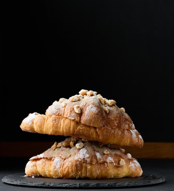 Baked croissant on a board and sprinkled with powdered sugar black table Appetizing pastries for breakfastx9