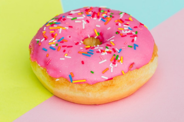 Baked donut with sprinkles on colored background