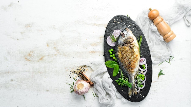 Photo baked dorado fish with vegetables on a black stone plate top view free space for your text