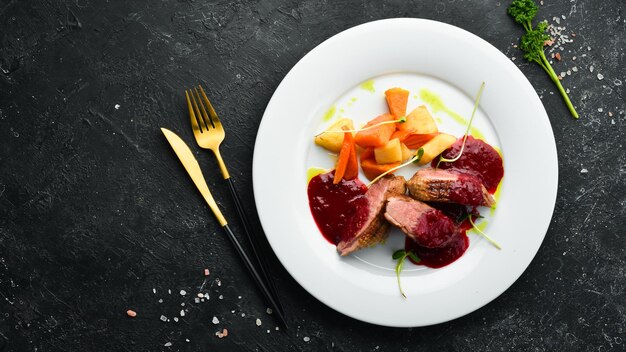 Baked duck breast with celery root and vegetables on a white plate. Top view. Rustic style.