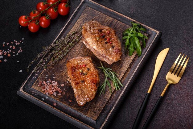 Baked duck breast with herbs and spices on a dark table. Fried meat ready to eat