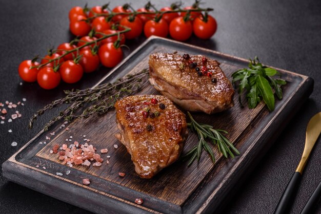 Baked duck breast with herbs and spices on a dark table. Fried meat ready to eat