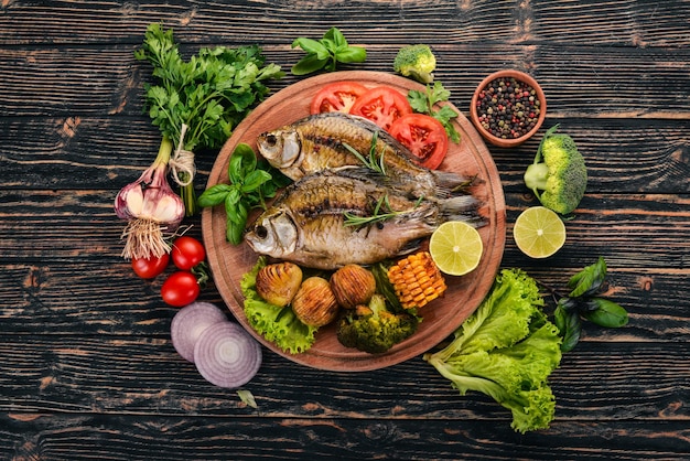 Baked fish with spices and vegetables Carp On a wooden background Top view Copy space