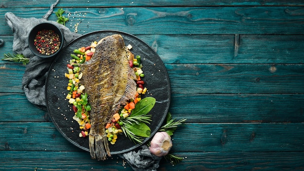 Photo baked flounder fish with vegetables on a black stone plate seafood top view free space for your text