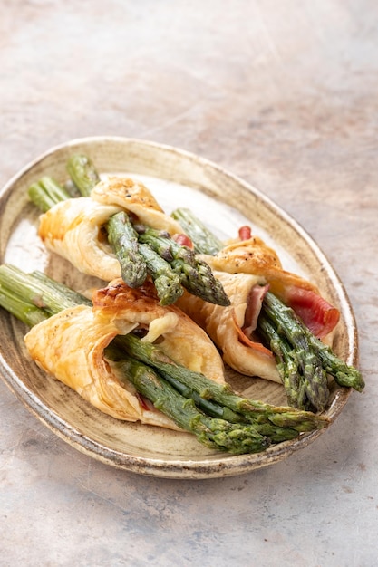 Baked green asparagus with ham and cheese in puff pastry