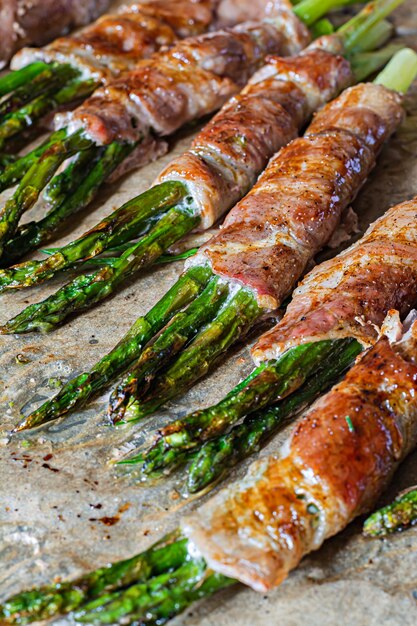 Baked green asparagus wrapped in crispy bacon. Light snack, side dish (garnish).