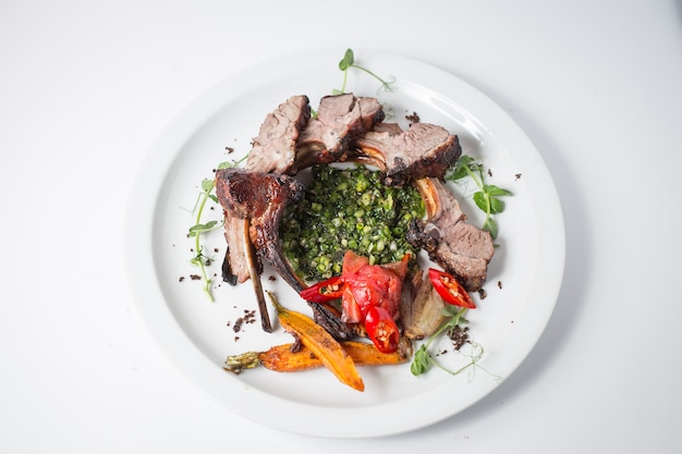 Baked lamb with carrot, onion, chili, green, carrot, green and tomatoes on white plate