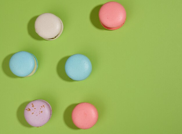 Baked macarons with different flavors on a green background, top view