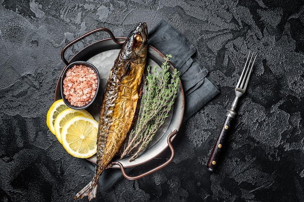 Baked Mackerel Scomber fish in steel tray with thyme and lemon Black background Top view