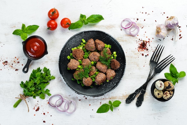 Baked meat balls with onions on a black plate Top view Free copy space