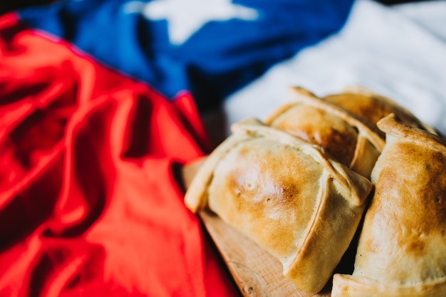 Baked meat chilean empanadas on the chilean flag. Copy space. Independence day. Selective focus