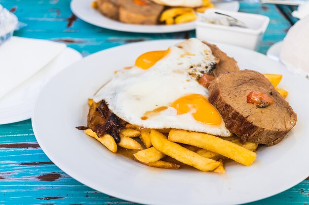 Baked meat french fries fried eggs and onion Protein meal