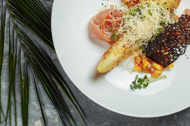 Baked melon with parmesan and jamon on a white plate