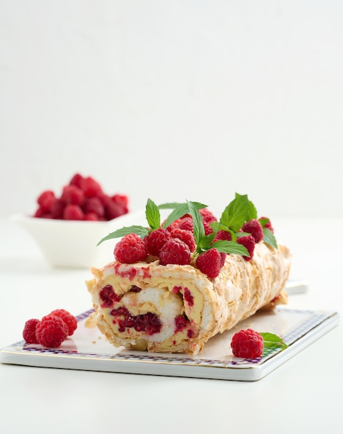 Baked meringue roll with cream and fresh red raspberry white background