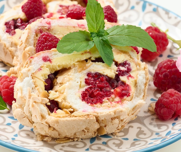 Baked meringue roll with cream and fresh red raspberry white background