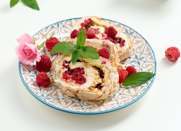 Baked meringue roll with cream and fresh red raspberry white background