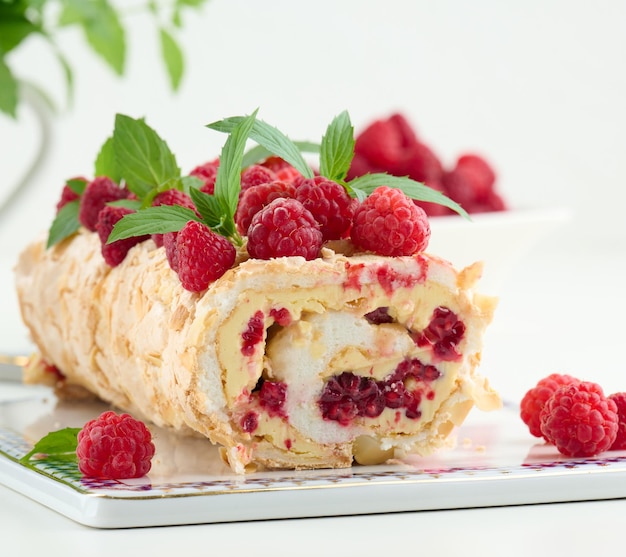 Baked meringue roll with cream and fresh red raspberry white background