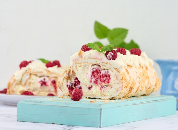 Baked meringue roll with cream and fresh red raspberry white backgroundx9