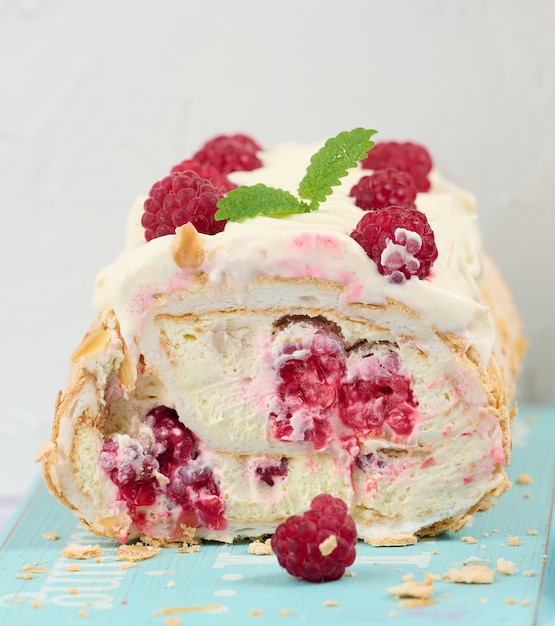 Baked meringue roll with cream and fresh red raspberry white backgroundx9