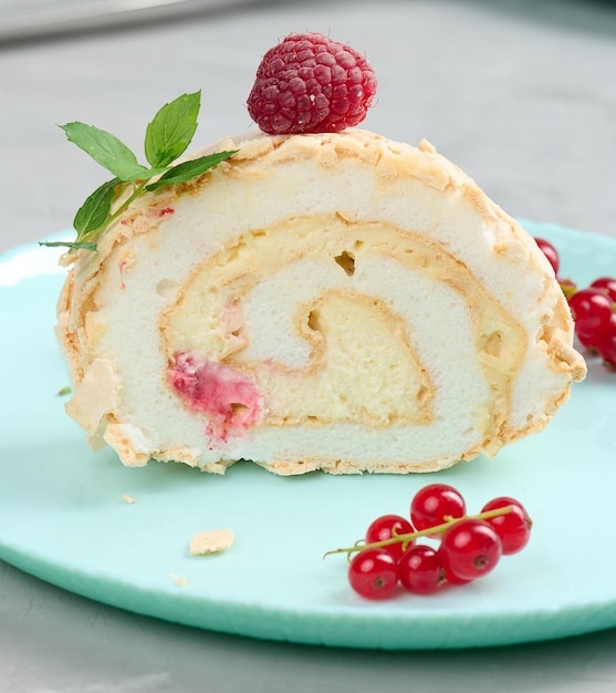 Baked meringue roll with red berries on a round plate white background