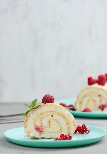 Baked meringue roll with red berries on a round plate white background