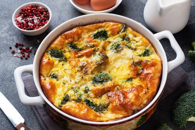 Baked omelet with broccoli in a ceramic dish. Dark concrete table. Healthy diet food dish.