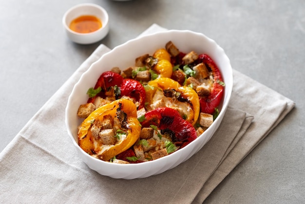 Baked peppers with cream cheese on a gray concrete background Grilled colorful peppers with cream cheese and croutons Delicious homemade picnic food