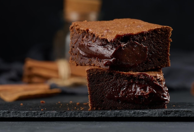 Baked pieces of chocolate brownie pie on black table delicious dessert