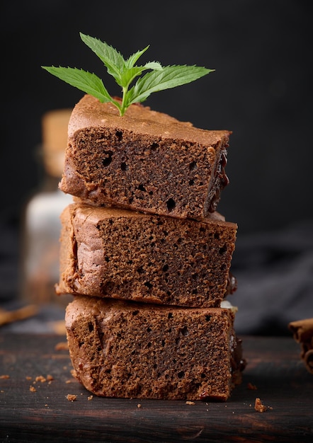 Baked pieces of chocolate brownie pie on black table delicious dessert