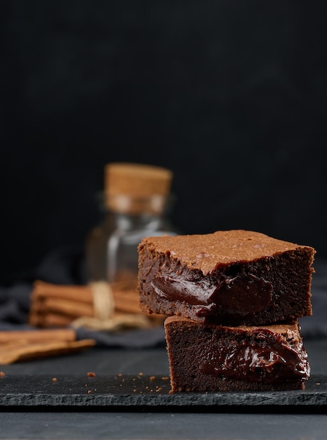 Baked pieces of chocolate brownie pie on black table delicious dessert