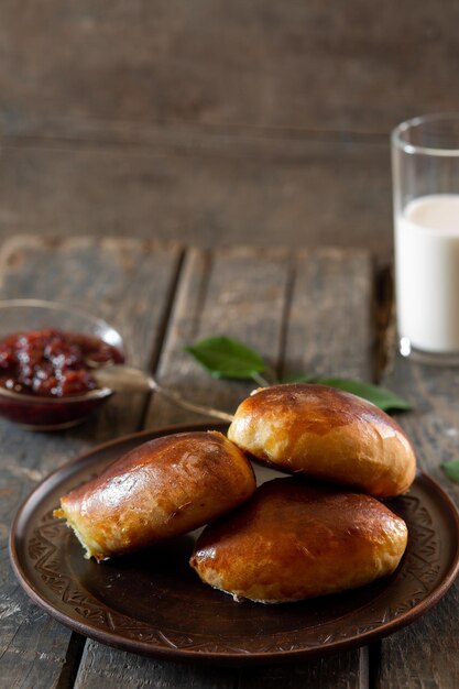 Baked pies on a clay plate on wooden boards cooking