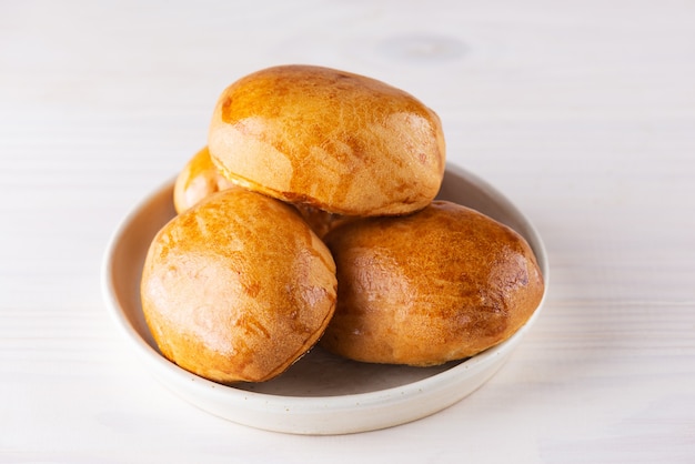 Baked pies on a plate on a wooden table.