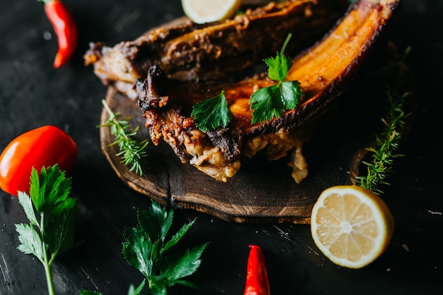 Baked pork ribs sitting on a rustic table with vegetables