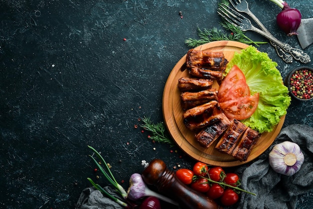 Baked pork ribs with vegetables on a board. Barbecue menu. Top view.