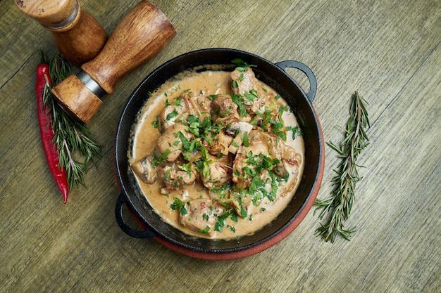 Baked potatoes with chicken in a creamy sauce in a pan on a . Top view on tasty food