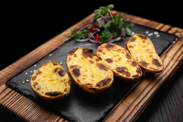 Baked potatoes on a wooden board with salt selective focus