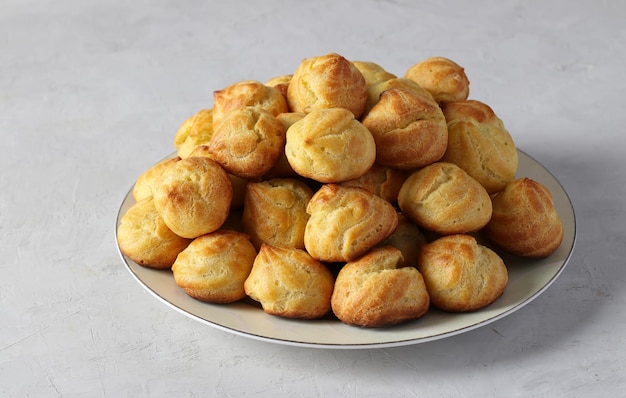 Baked profiteroles from puff pastry choux pastry balls on a gray background