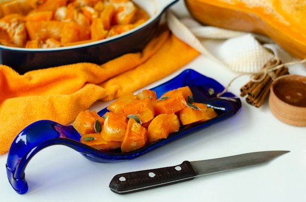 Baked pumpkin on a hand crafted blue serving plate on white background.