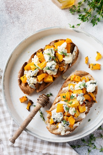 Baked pumpkin sandwich with dorblu cheese with blue mold and thyme on a concrete background