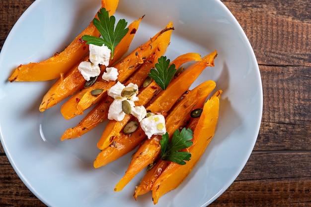 Baked pumpkin slices with cottage cheese in blue plate on wooden background autumn seasonal recipes with pumpkin